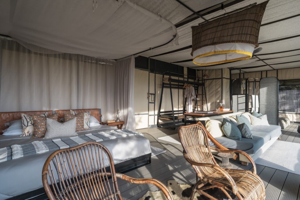 Boho bedroom lounge inside a tent with two daybeds, throw pillows, and wicker chairs.