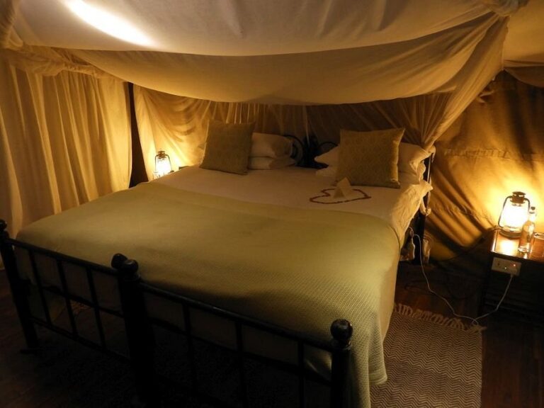 King bed in a cozy canopy tent with warm lighting and lanterns on the nightstands